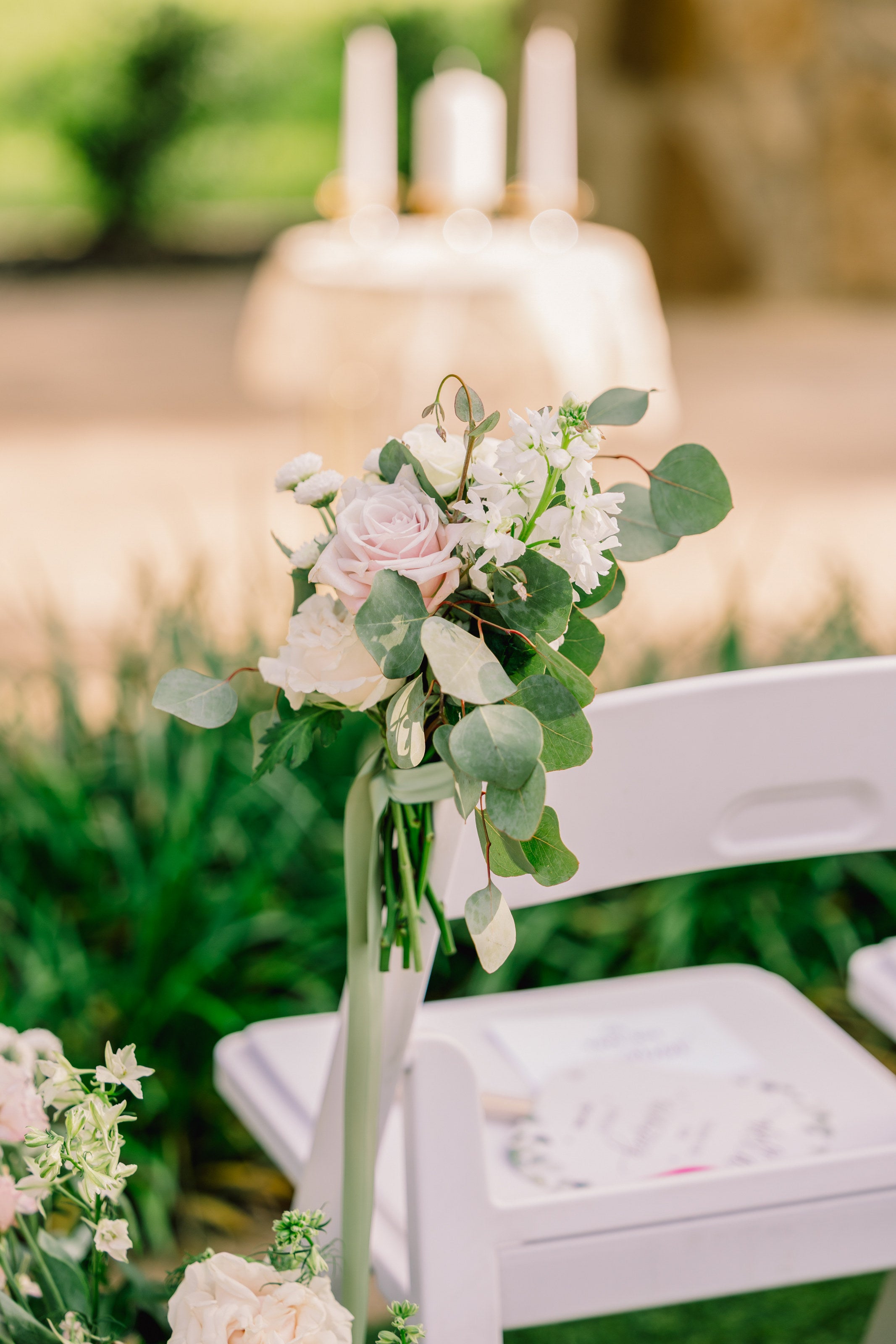 Aisle marker close-up at The Springs Alvarado with a blush garden rose, white snapdragon, and trailing eucalyptus tied to a garden chair, by B.blumen