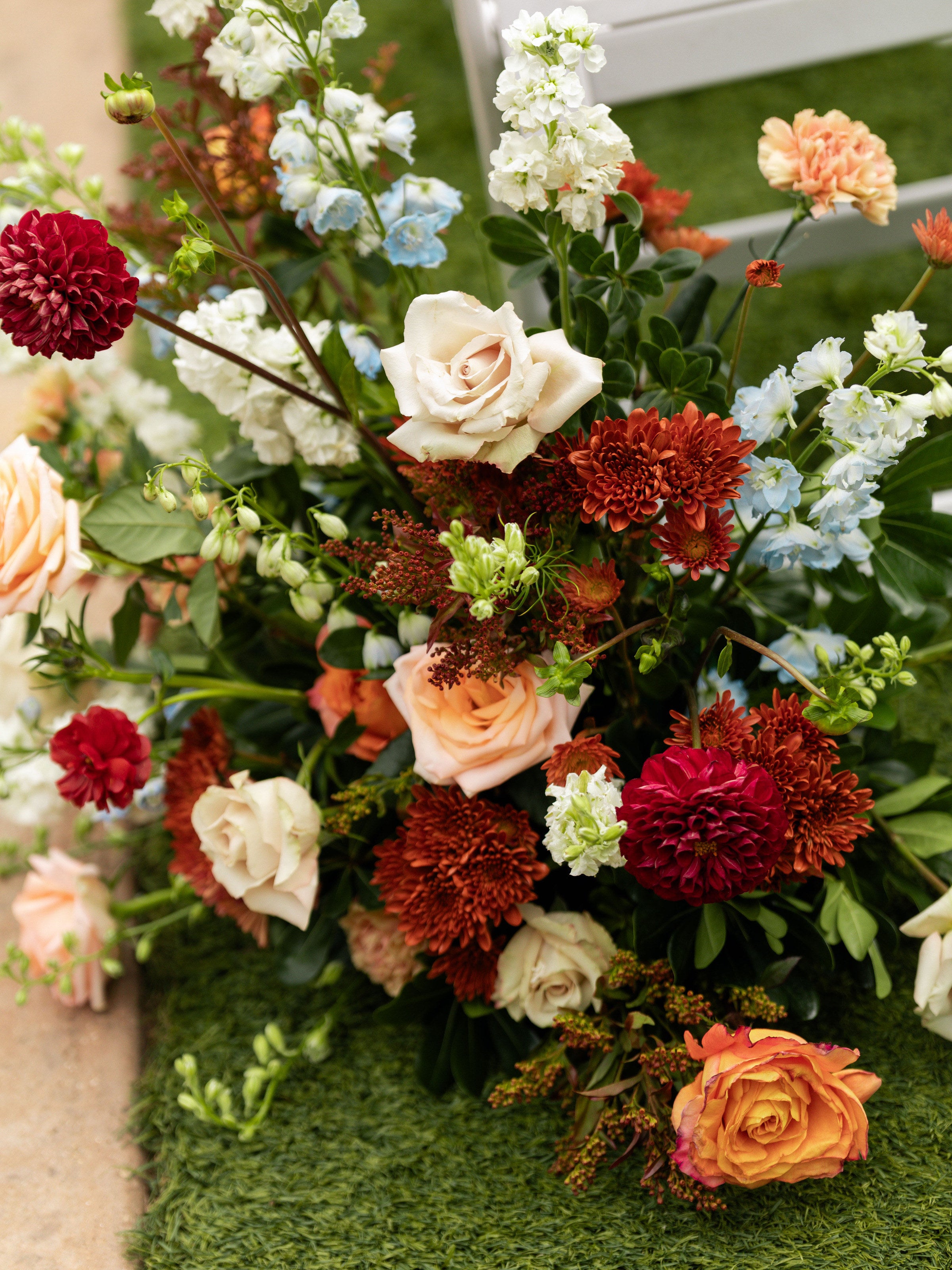 Ground floral cluster at The Springs Alvarado in burgundy, rust, coral and cream against the lawn, by B.blumen