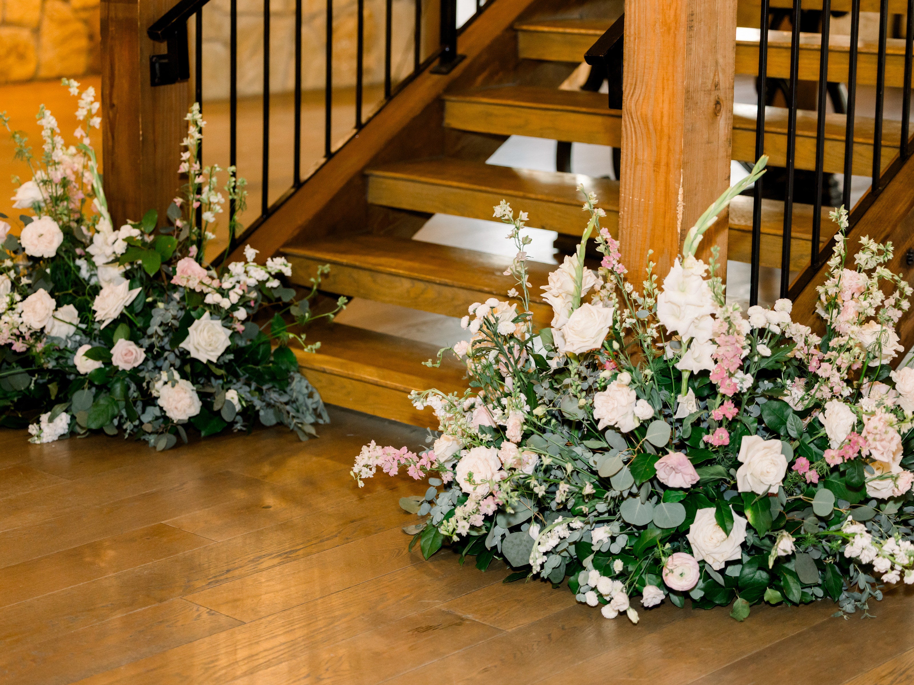 Ground arrangements in white, blush and cream banked at the foot of the wood-and-iron staircase at Timberview Lodge, by B.blumen