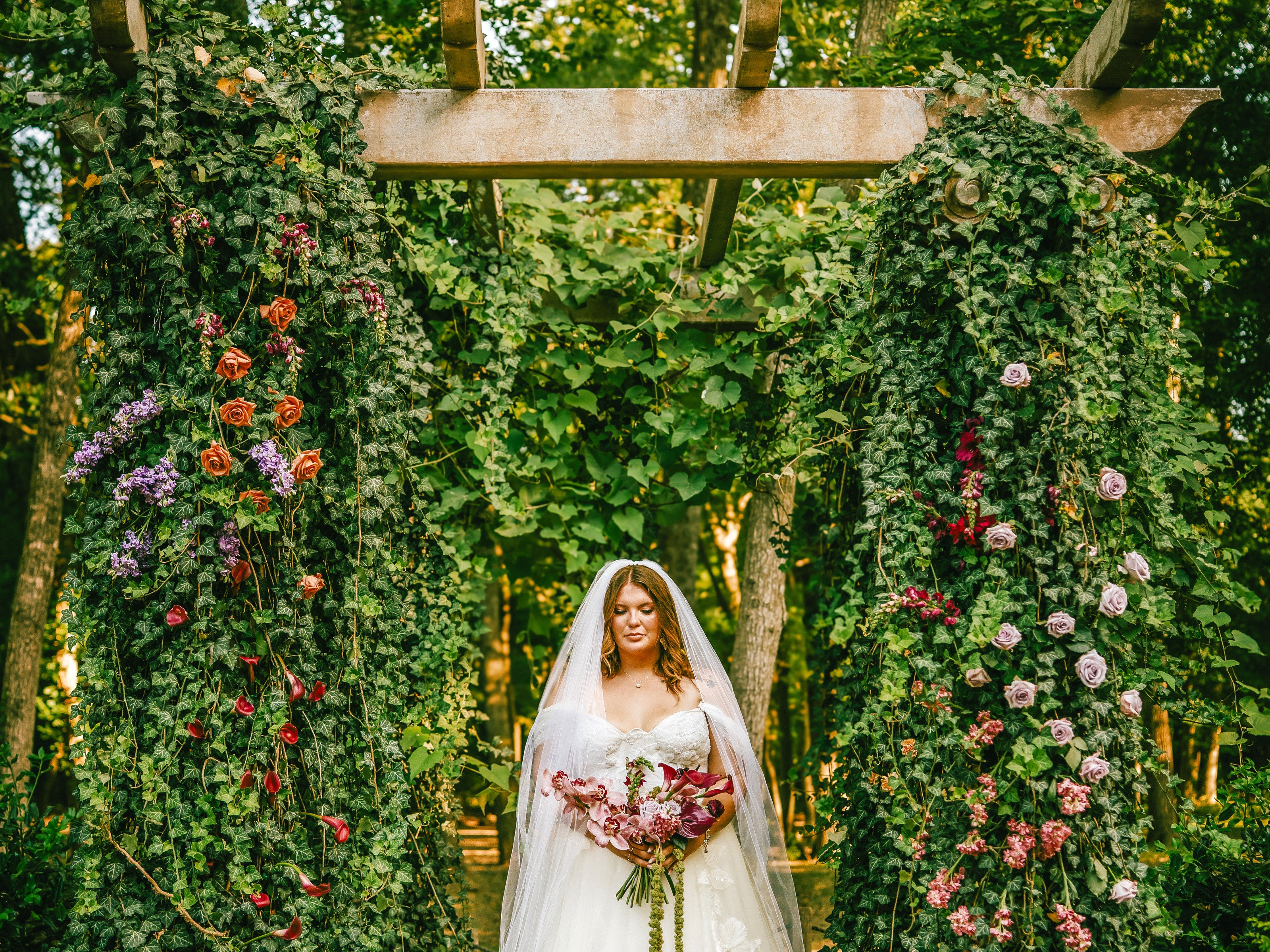 Bride at the greenery and garden-rose ceremony arbor at The Springs Waxahachie, florals by B.blumen