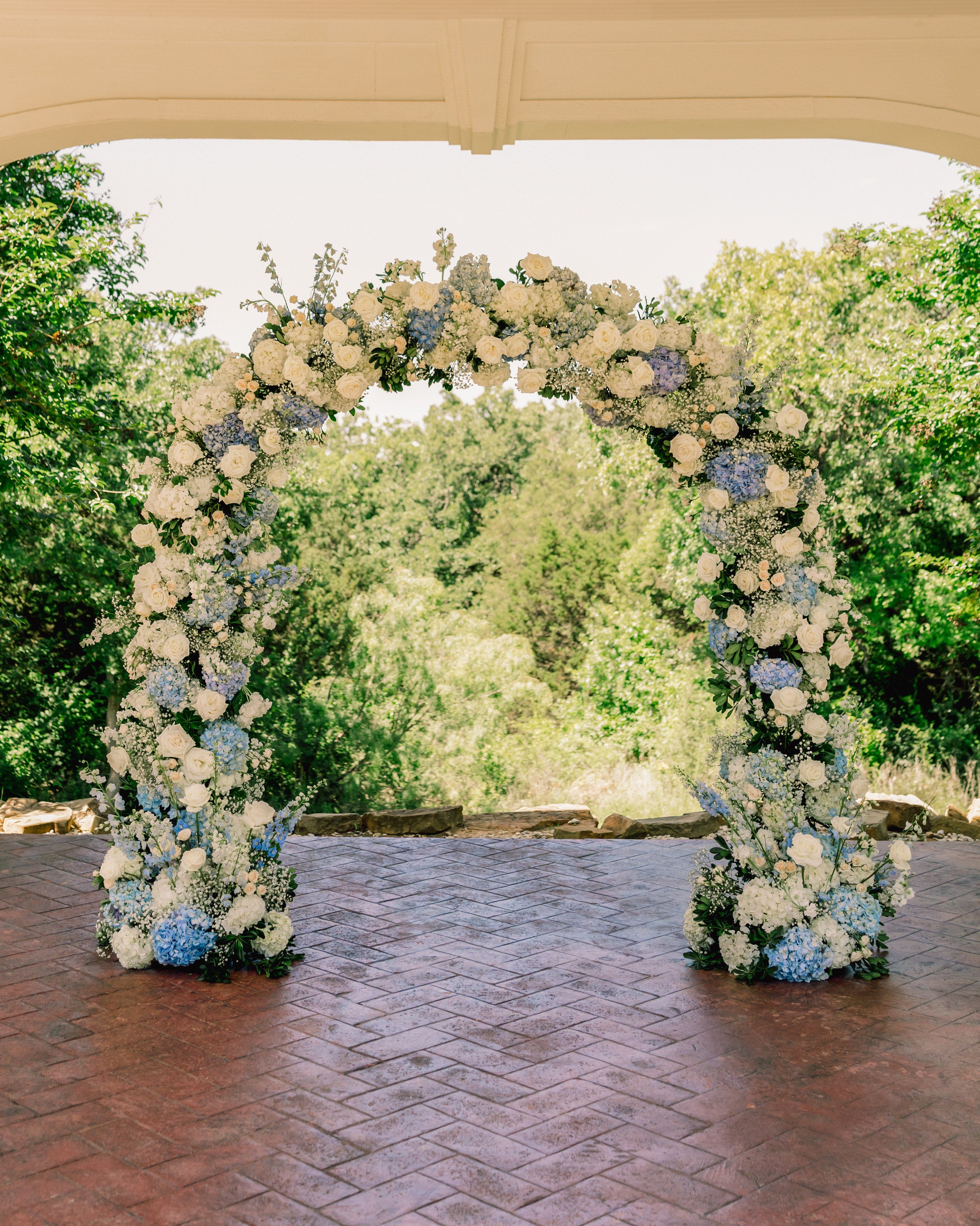 Blue and white floral arch on the brick under the Parker Manor portico by B.blumen