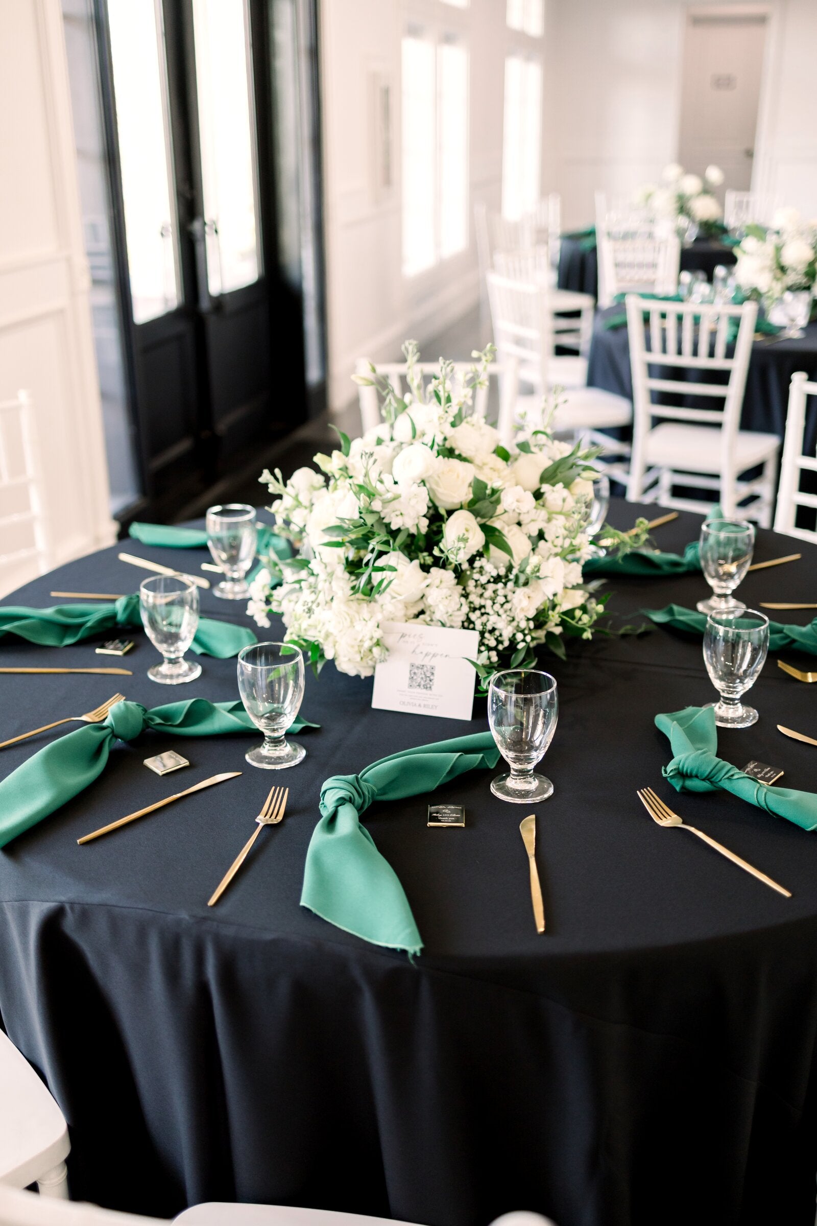 Round reception table at Parker Manor with navy linen, emerald napkins, white-and-green floral centerpiece, gold flatware, by B.blumen