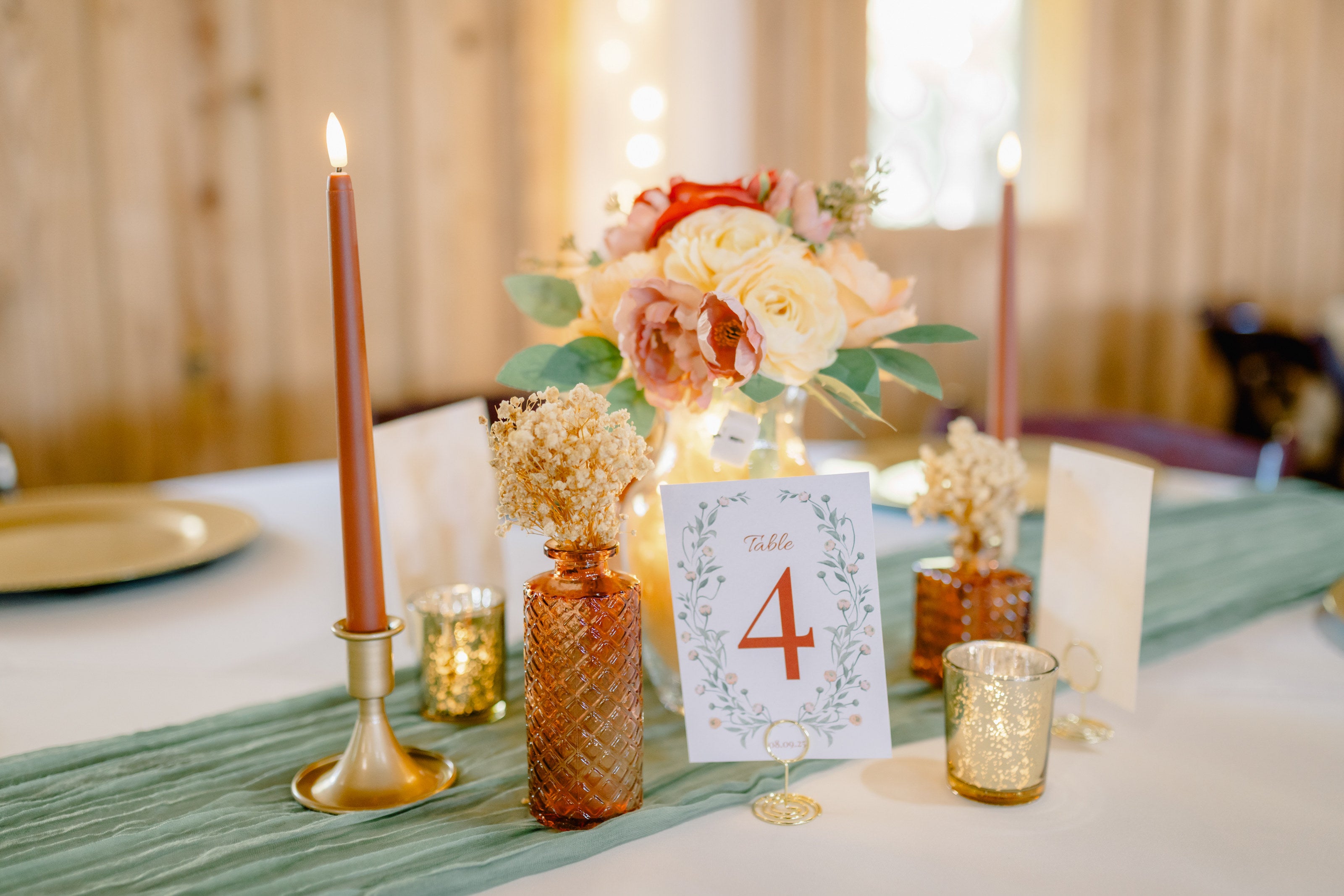 Centerpiece detail at Westwood Hall with peach and blush florals in amber bud vases, sage runner, and gold mercury candle votives by B.blumen