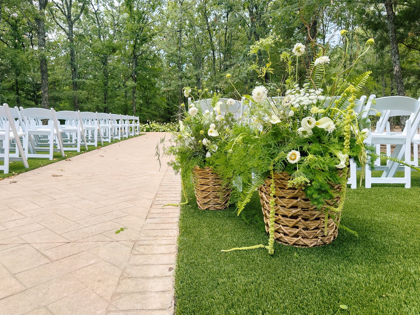 White and green outdoor ceremony aisle at The White Sparrow with woven-basket arrangements, by B.blumen