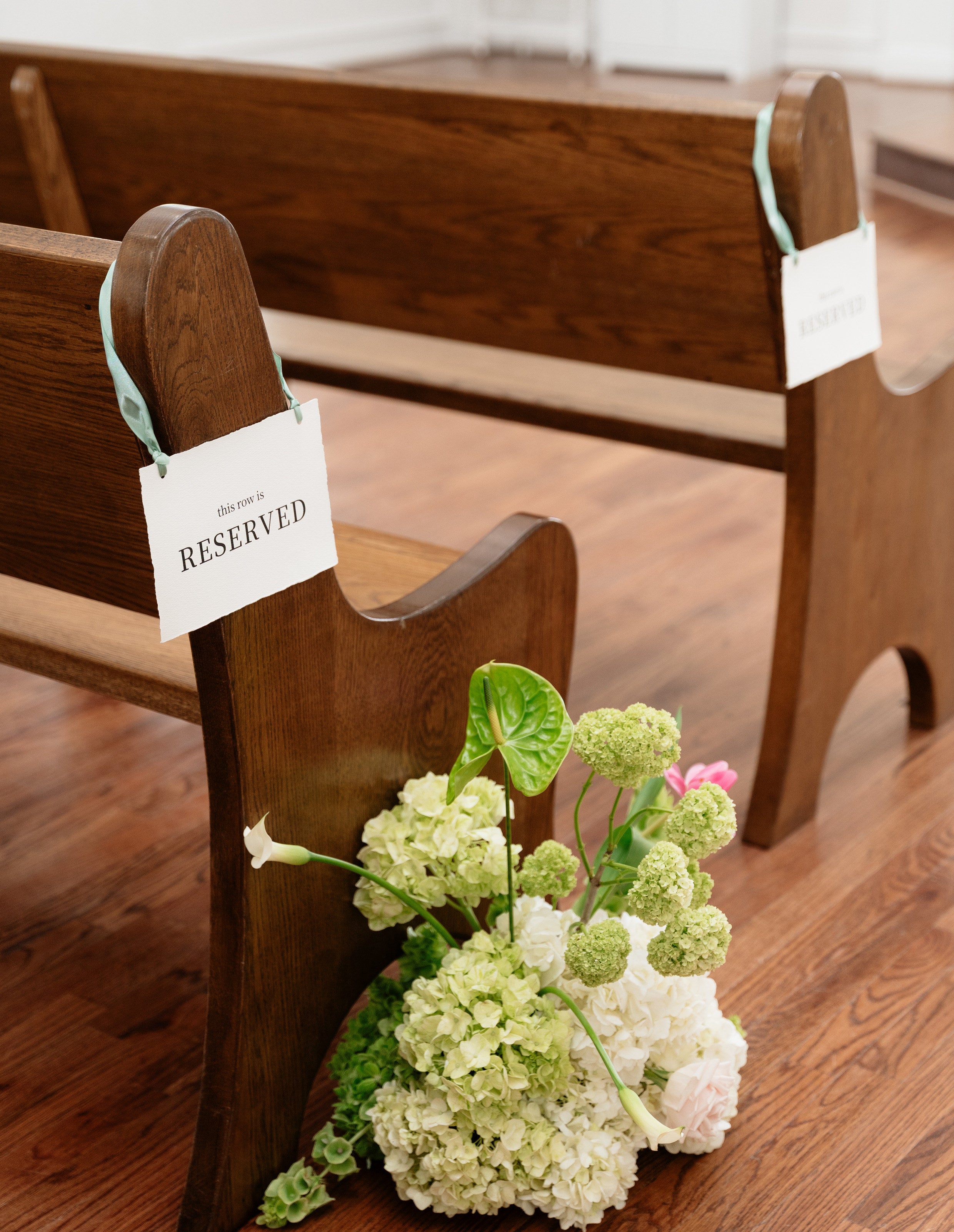 Reserved-pew detail at The White Sparrow chapel with a white and green hydrangea arrangement, by B.blumen