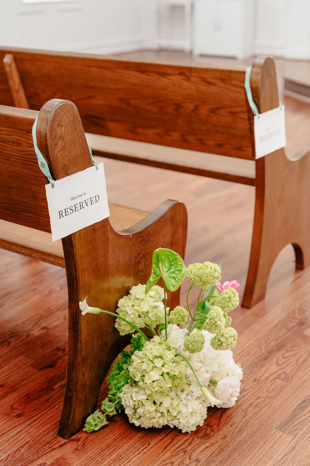 Reserved-pew detail at The White Sparrow chapel with a white and green hydrangea arrangement, by B.blumen
