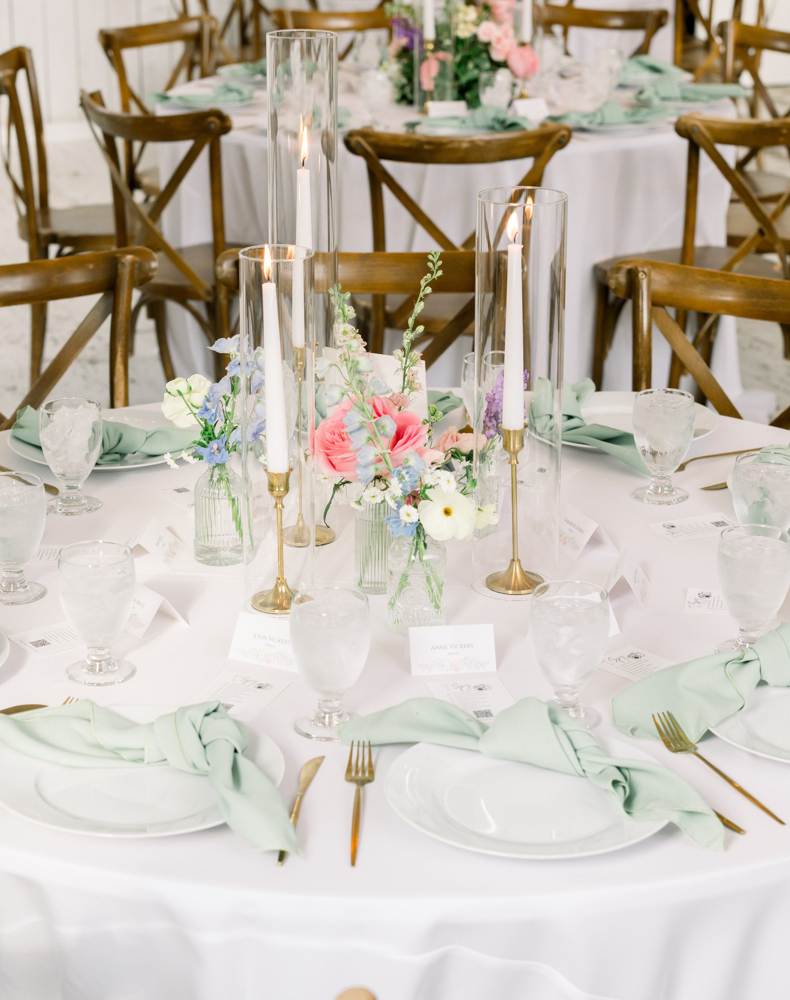 Round reception table at The White Sparrow with a low blush-and-white centerpiece, sage napkins, and cross-back chairs, by B.blumen