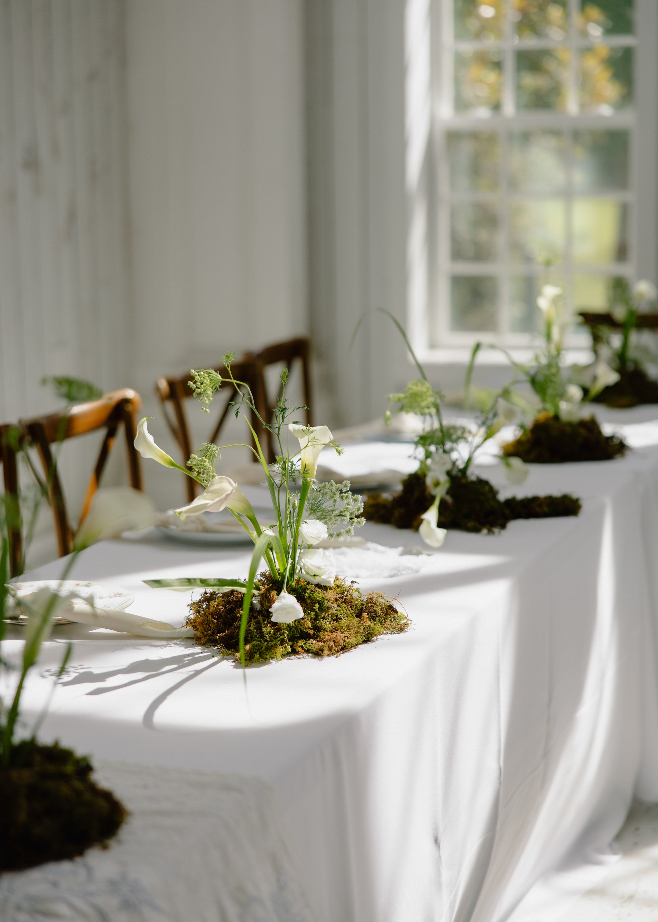 Reception table at The White Sparrow styled in white and green with a moss runner centerpiece, by B.blumen