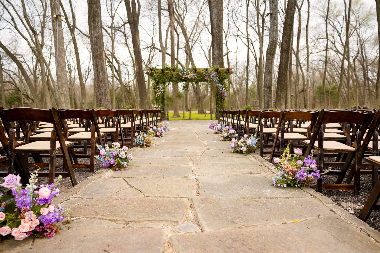 Pastel ceremony aisle at The Springs Waxahachie with pergola arch and pink-to-blue floral aisle markers by B.blumen