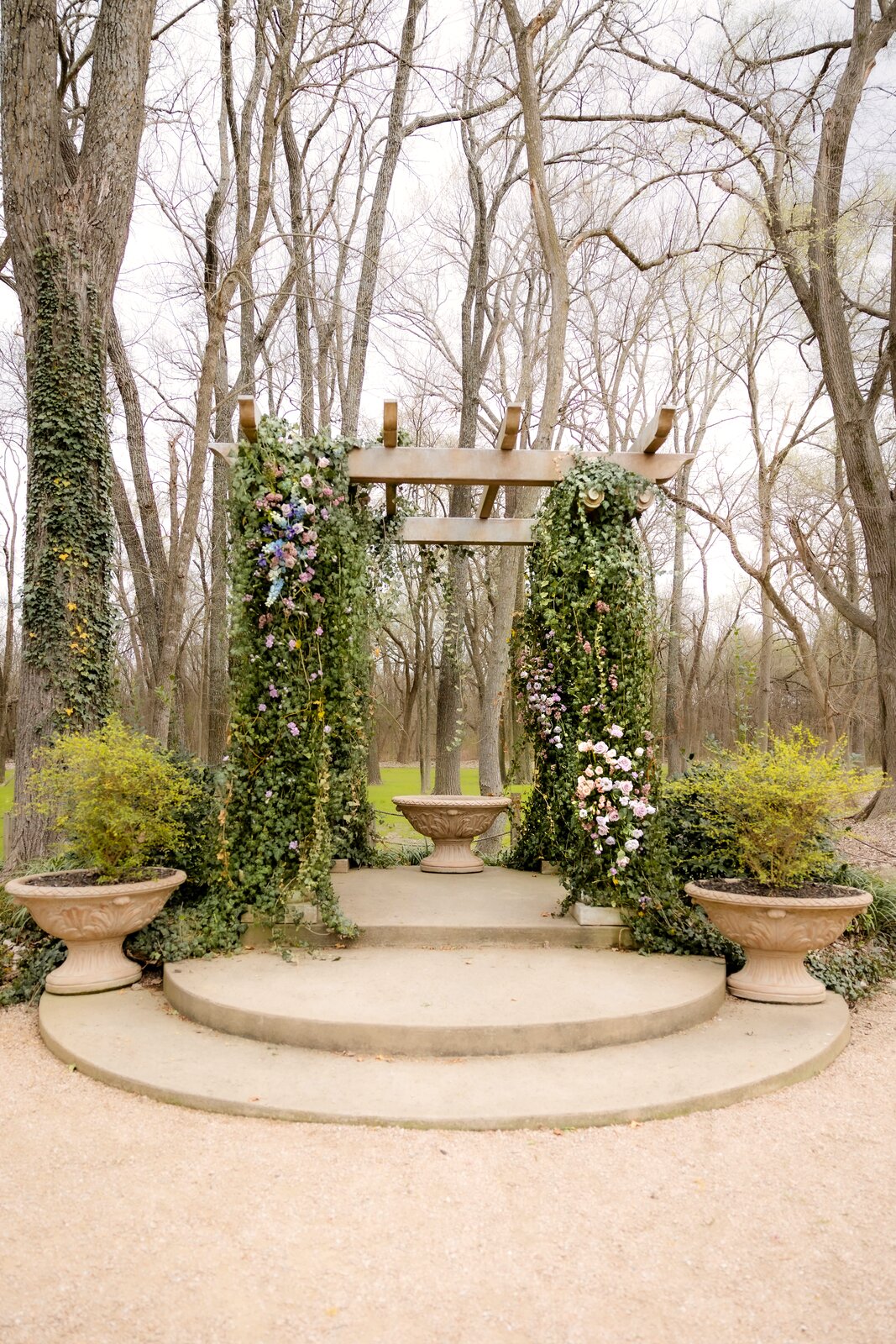 Pastel pergola altar at The Springs Waxahachie with terracotta urns and cascading florals by B.blumen