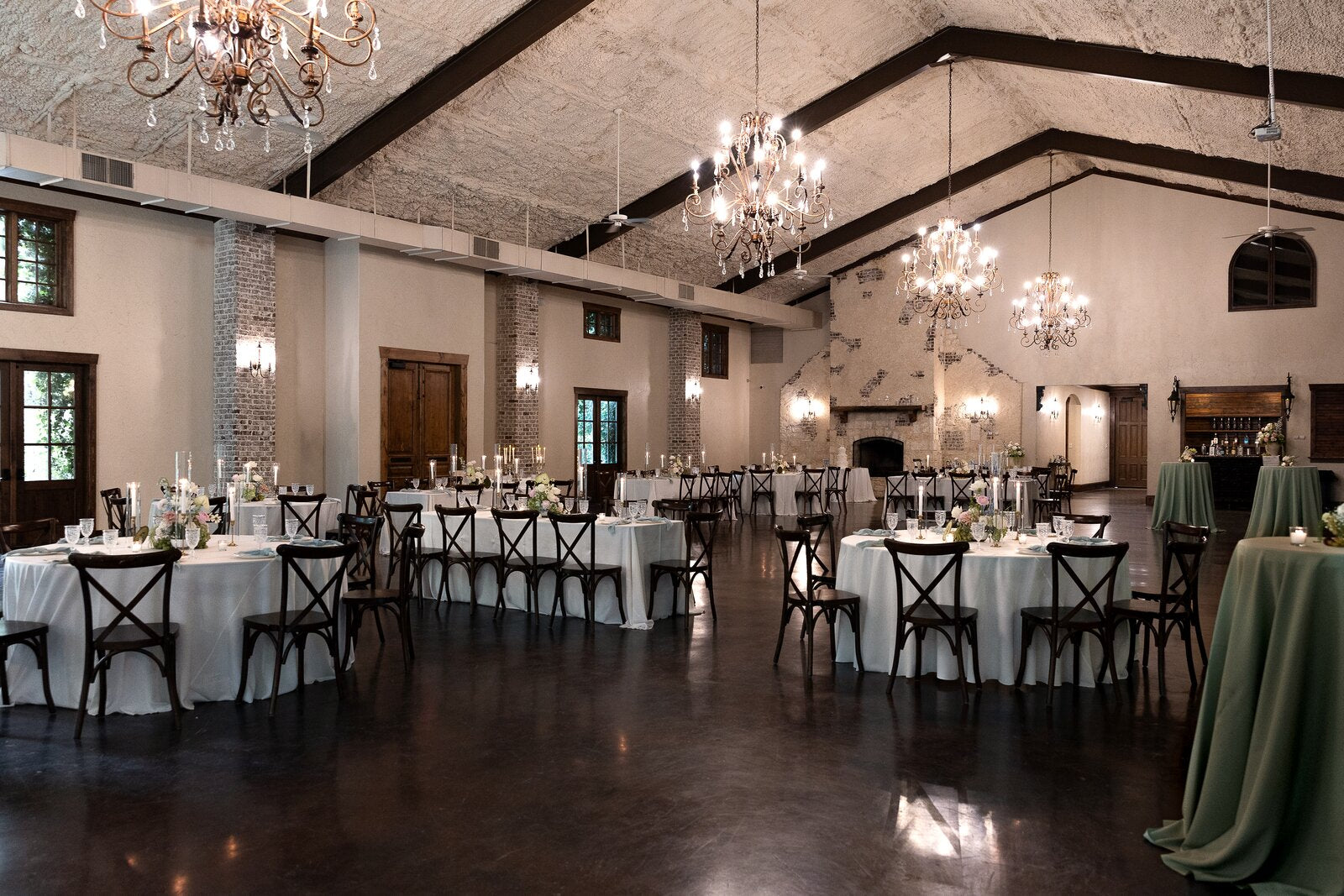 Reception hall at The Springs Waxahachie with stone walls, wooden beams, and chandeliers