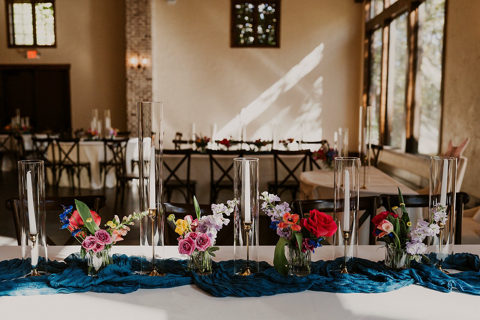 Sweetheart table at The Springs Waxahachie with vibrant multicolor florals and a dark blue runner by B.blumen