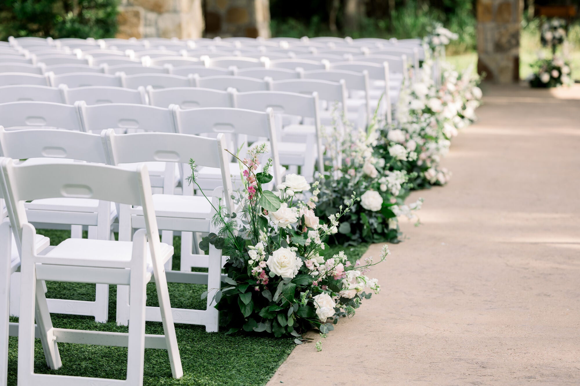 Pastel ceremony aisle at The Springs Alvarado with ground florals of white roses, snapdragons, and pink delphinium running the length of the path, by B.blumen
