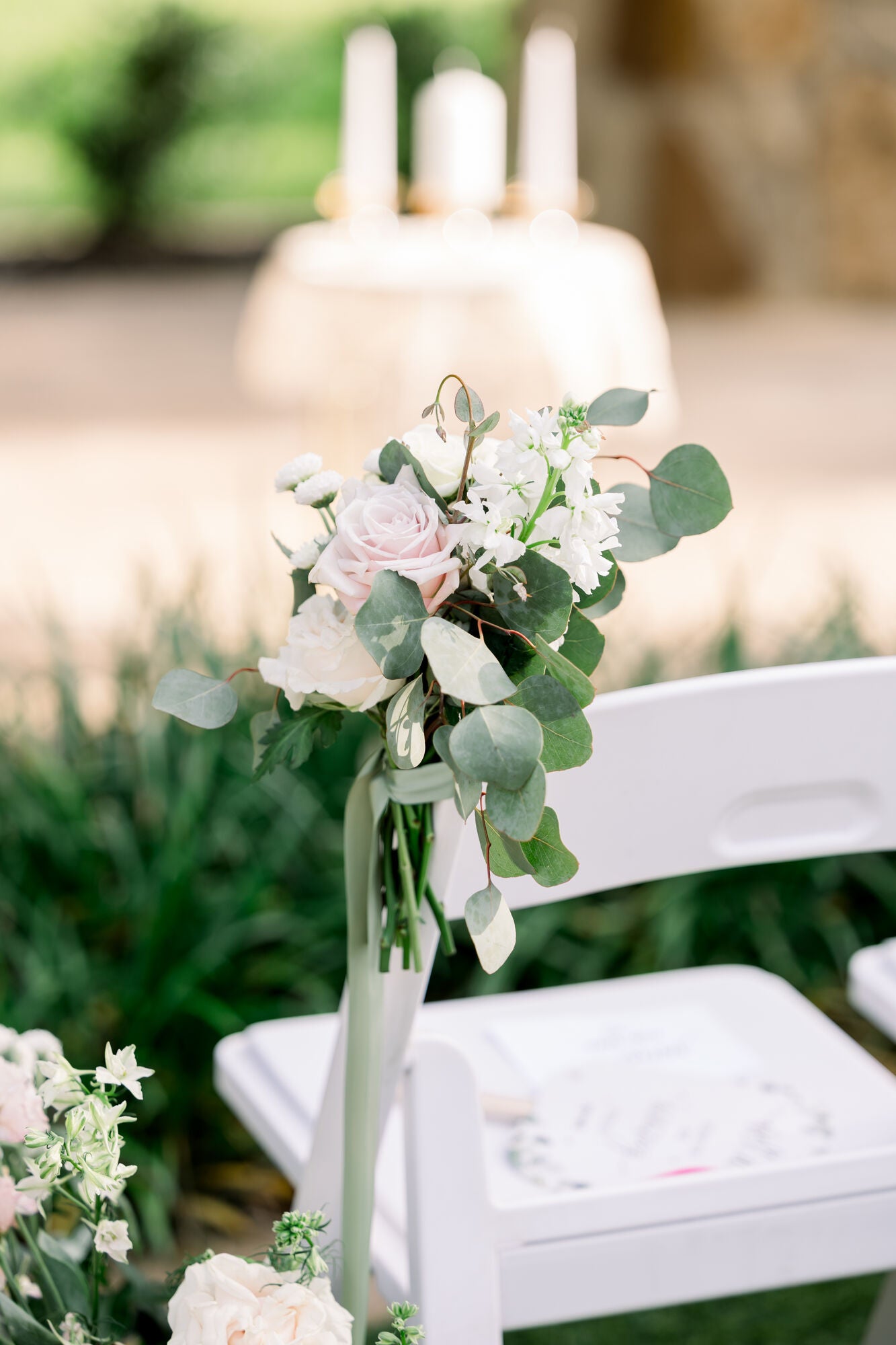 Aisle marker close-up at The Springs Alvarado with a blush garden rose, white snapdragon, and trailing eucalyptus tied to a garden chair, by B.blumen
