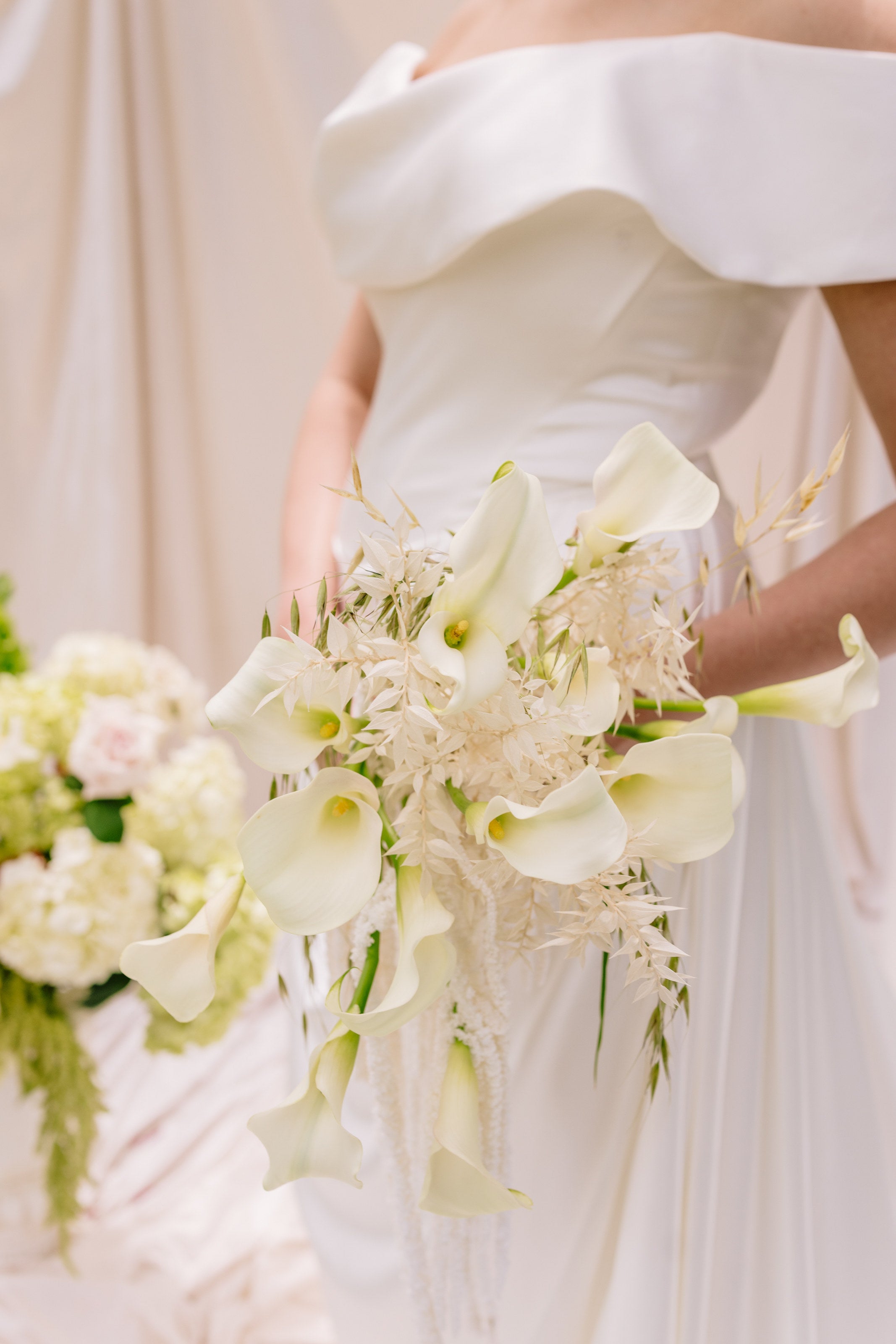 Cascading calla lily bridal bouquet in white against the gown at The Springs Rockwall, by B.blumen