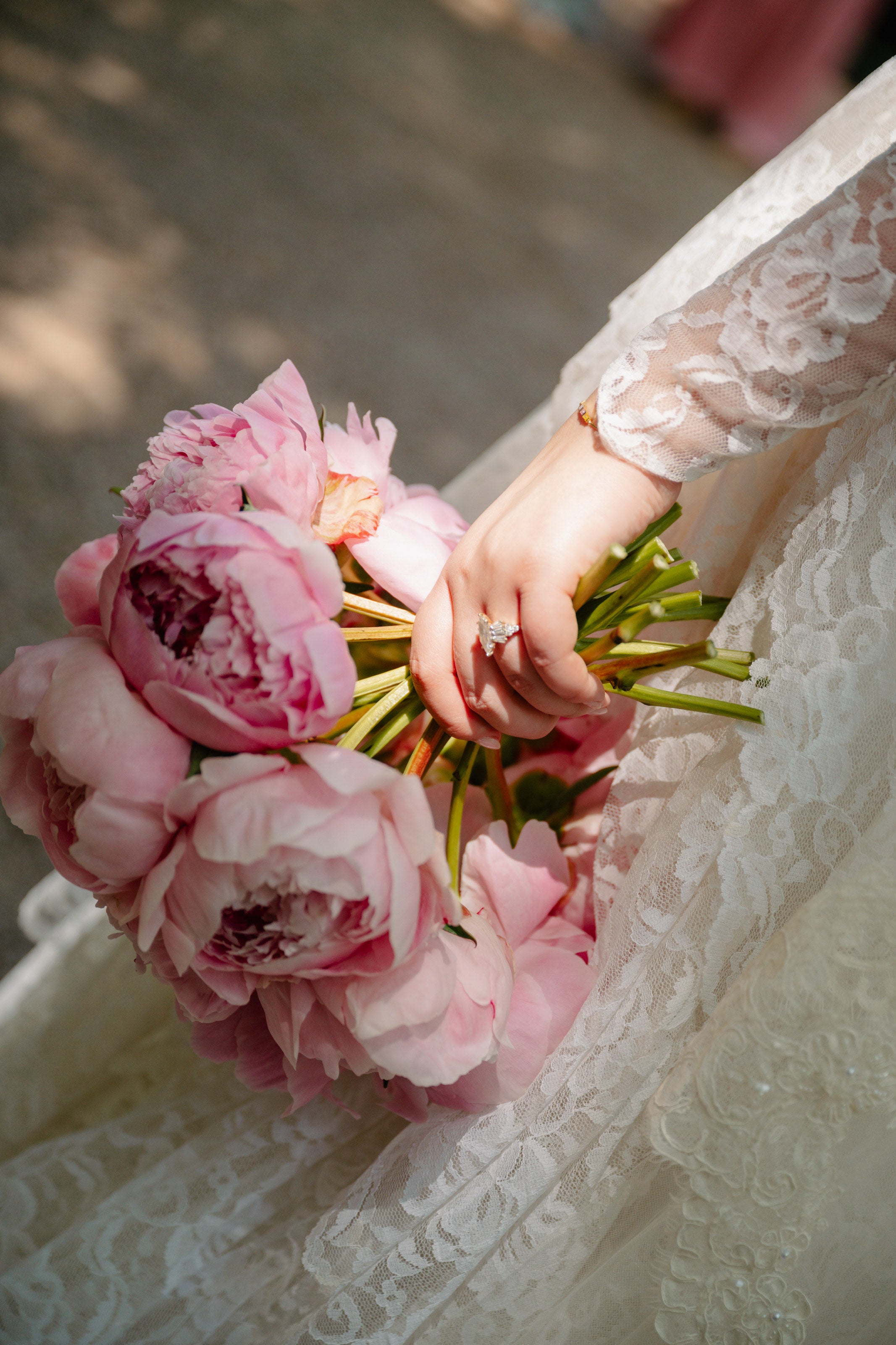 Pink peony bridal bouquet held against lace at The Springs Waxahachie by B.blumen