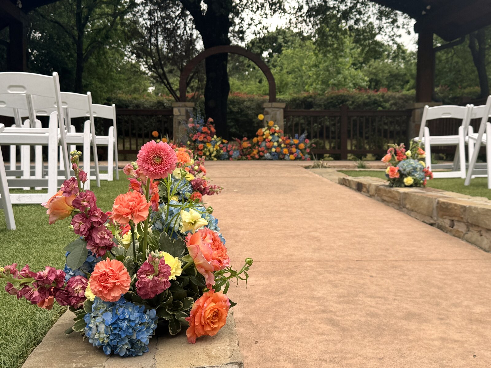 Aisle marker close-up at The Springs Weatherford with pink gerbera, orange ranunculus, hydrangea, and yellow stock by B.blumen