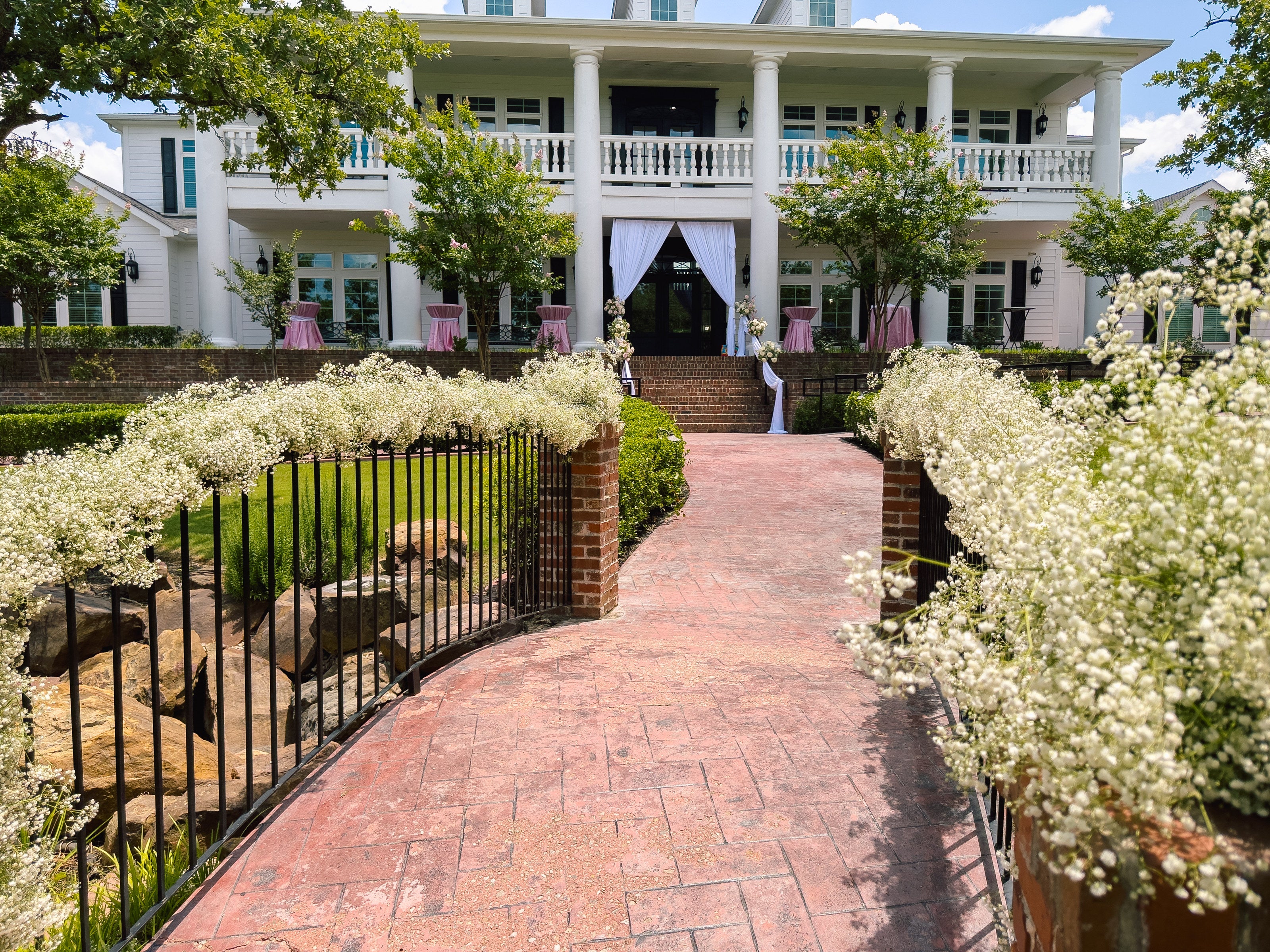 Brick path to the Parker Manor house lined with white floral hedges by B.blumen