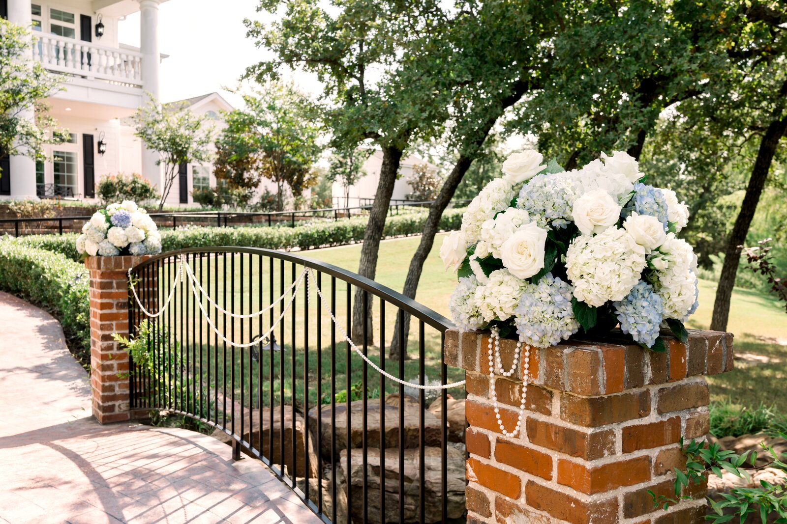 Brick gate-pier hydrangea arrangement at Parker Manor entrance with the columned manor in the background by B.blumen