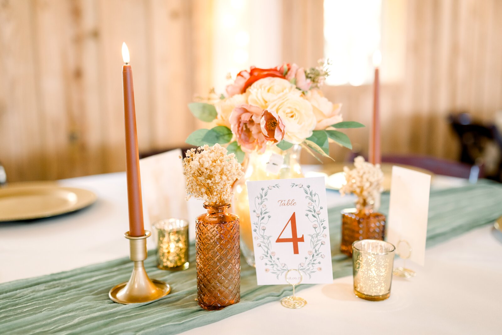 Centerpiece detail at Westwood Hall with peach and blush florals in amber bud vases, sage runner, and gold mercury candle votives by B.blumen
