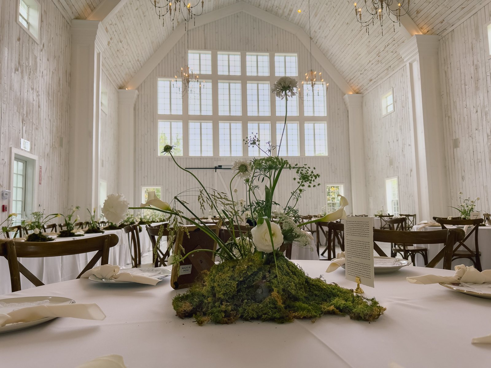 Reception table at The White Sparrow styled in white and green with a moss runner centerpiece, by B.blumen