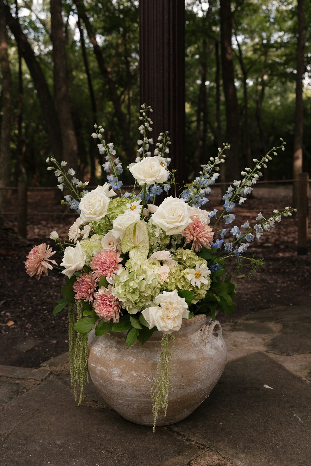 Pedestal floral arrangement at The Springs Waxahachie with white roses, hydrangea, pink dahlias, and blue delphinium by B.blumen