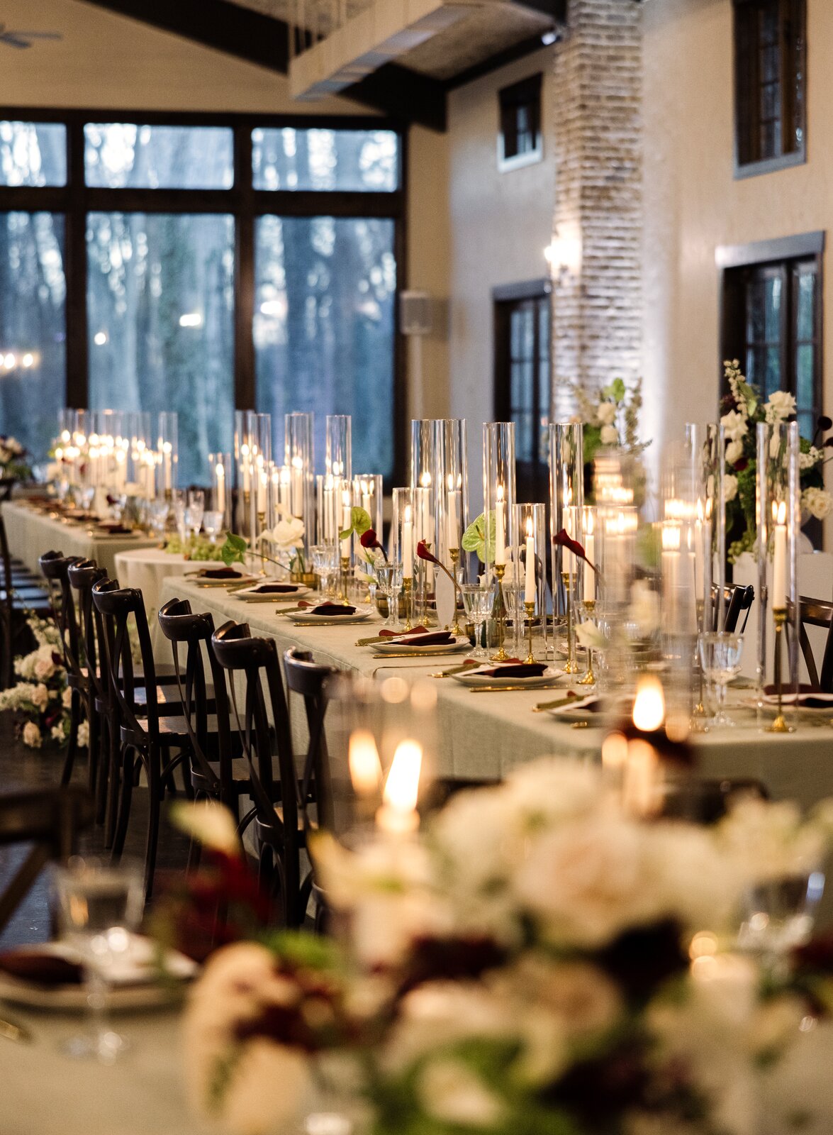 Long candle-lit reception table at The Springs Waxahachie with burgundy and white florals by B.blumen